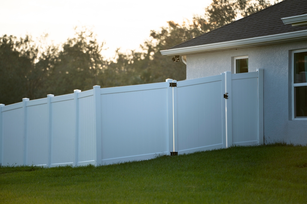 White vinyl fence gate on a green lawn